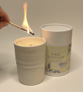 candle in a hand thrown pot being lit with a match