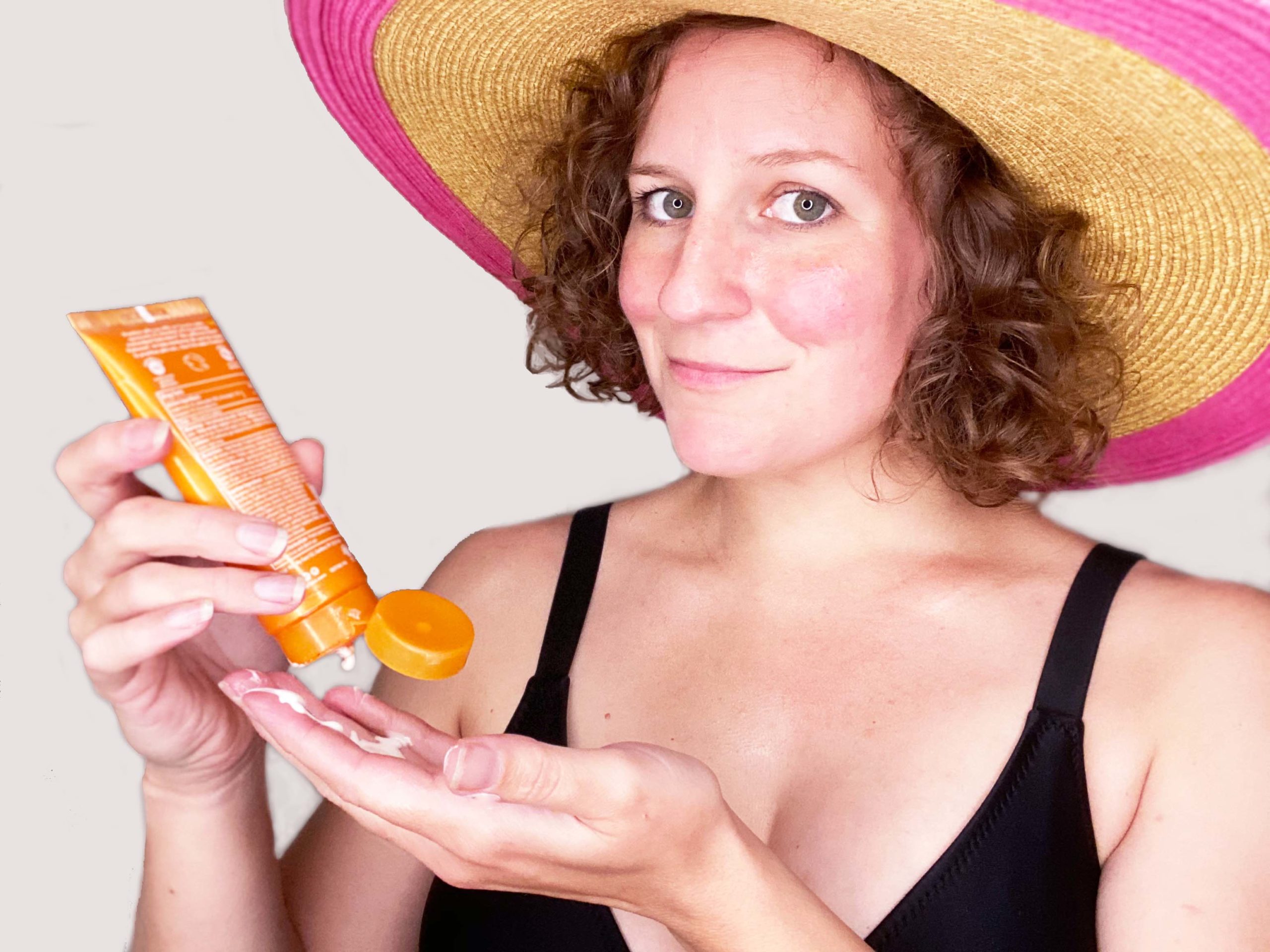 woman wearing sun hat applying sunscreen to hands