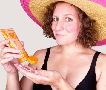 woman wearing sun hat applying sunscreen to hands